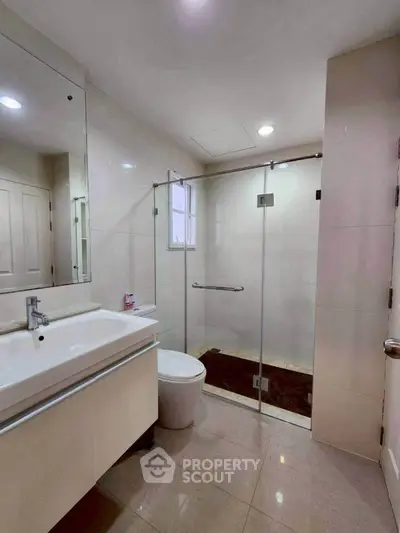 Modern bathroom with glass shower and sleek vanity in a contemporary home.