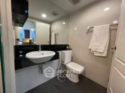 Modern bathroom with sleek fixtures and large mirror in contemporary apartment.