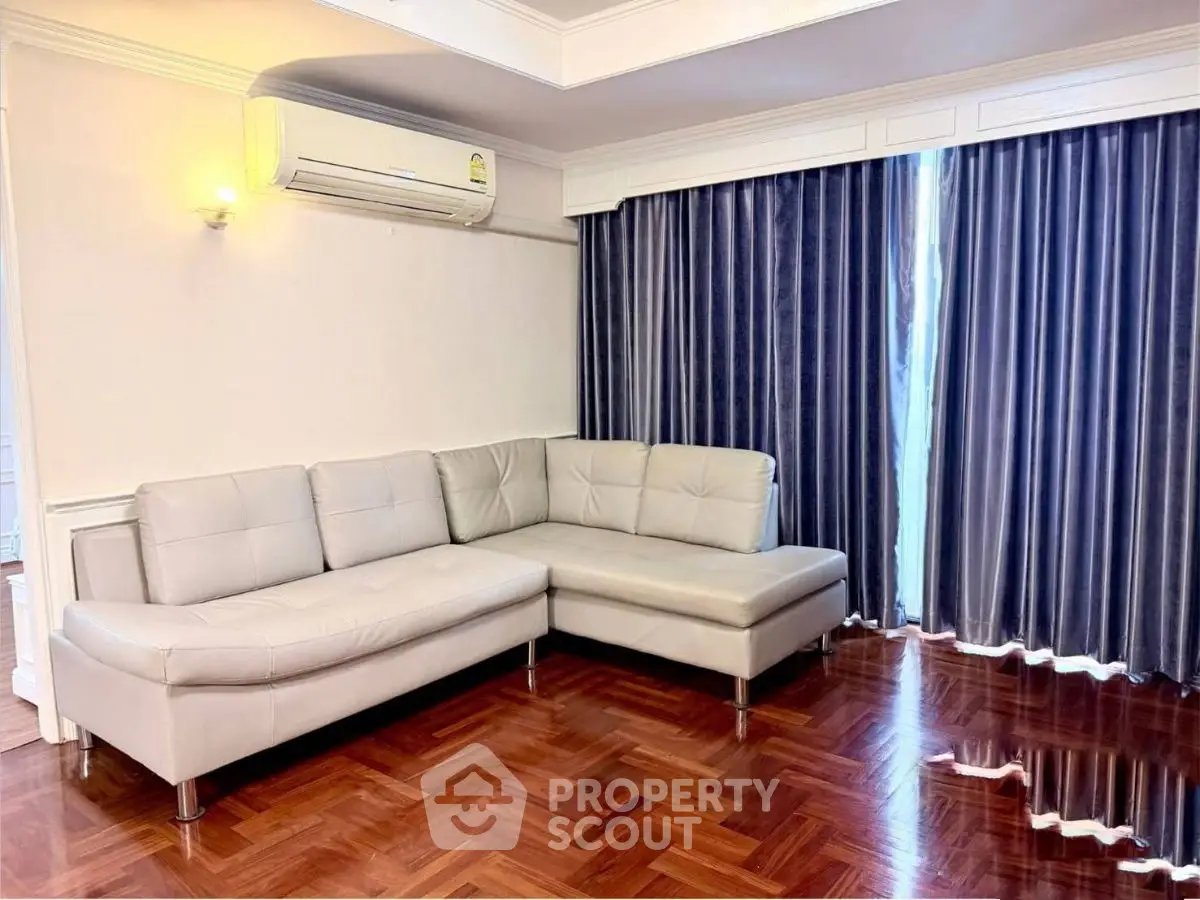 Spacious living room with elegant parquet flooring and modern L-shaped sofa, featuring large windows with stylish curtains.