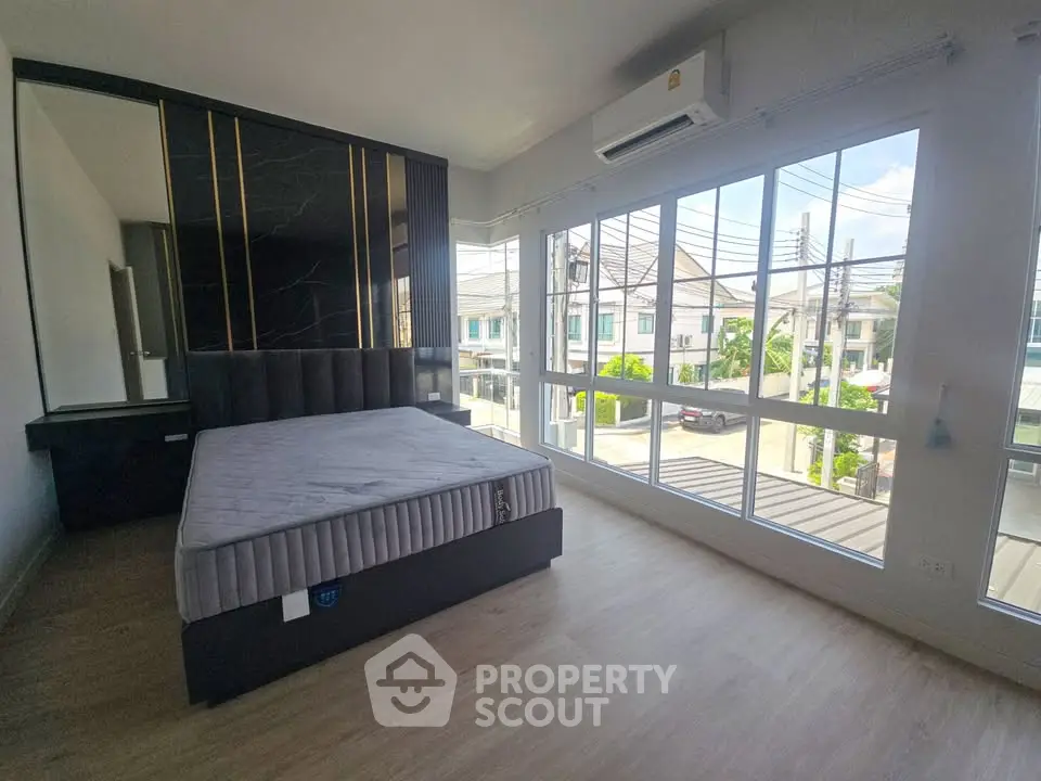 Spacious bedroom with large windows offering a bright and airy atmosphere in a modern home.