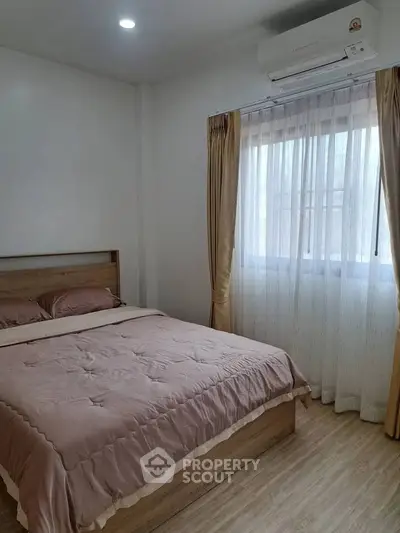 Cozy bedroom with natural light and modern air conditioning unit, perfect for relaxation.