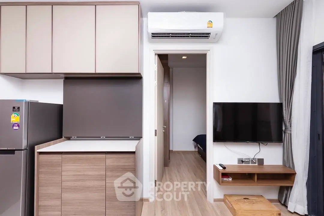 Modern apartment interior with sleek kitchen and cozy living area, featuring wood flooring and contemporary design.