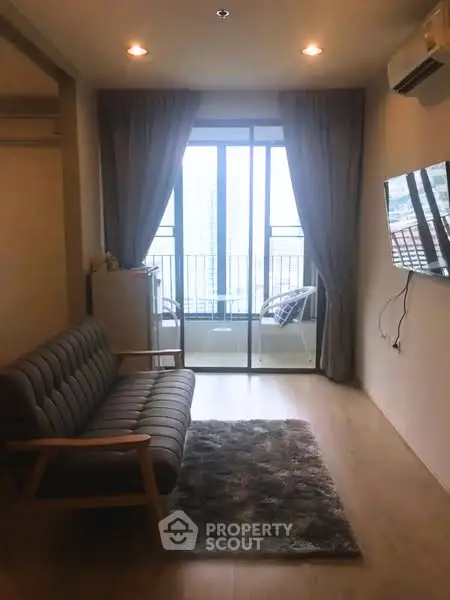 Cozy living room with balcony view, featuring modern sofa and wall-mounted TV.