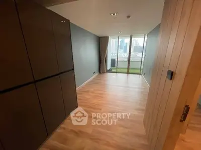 Spacious modern living room with wooden flooring and city view balcony.