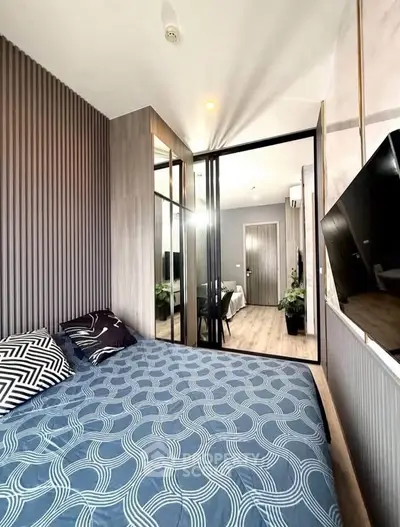 Modern bedroom with stylish decor and mirrored closet doors in a cozy apartment.