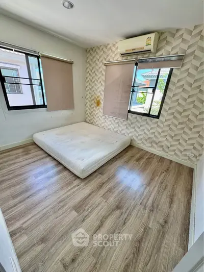 Spacious bedroom with modern flooring and large windows for natural light.