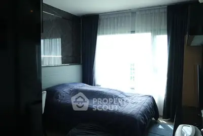 Modern bedroom with dark curtains and sleek design, featuring a cozy bed and natural light.