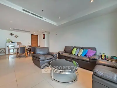 Spacious modern living room with leather sofas and vibrant cushions in open-plan layout.