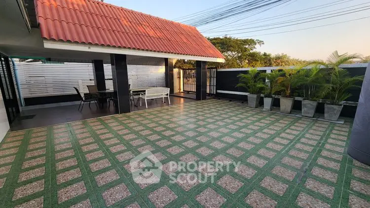 Spacious tiled patio with covered seating area and lush greenery