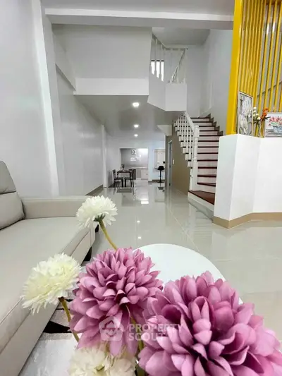 Modern living room with elegant staircase and floral decor