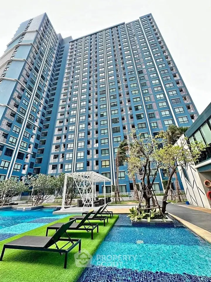 Luxurious high-rise building with modern pool and lush landscaping, perfect for urban living.