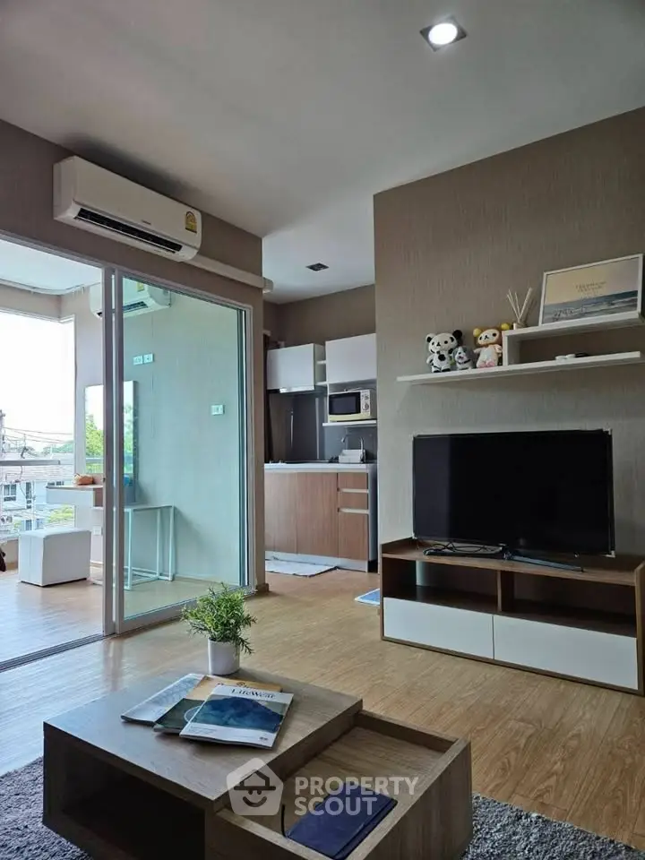 Modern living room with open kitchen, featuring stylish decor and natural light from large windows.