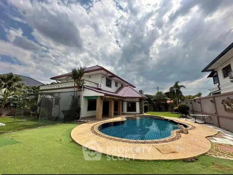Luxurious villa with private pool and lush garden under a dramatic sky.