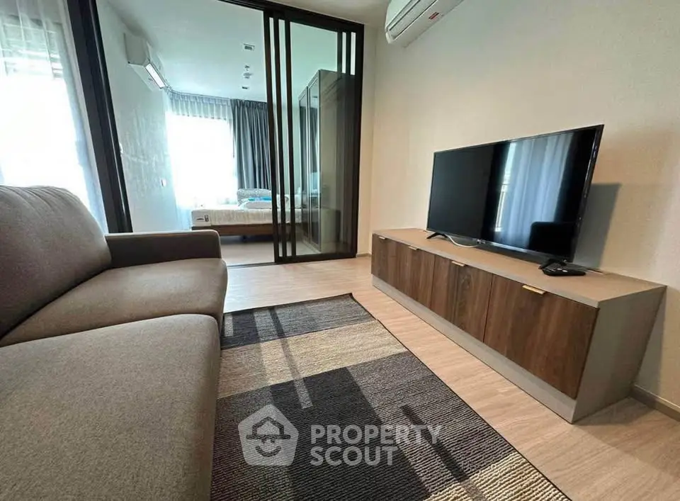 Modern living room with sleek furniture and a view into a cozy bedroom, perfect for urban living.