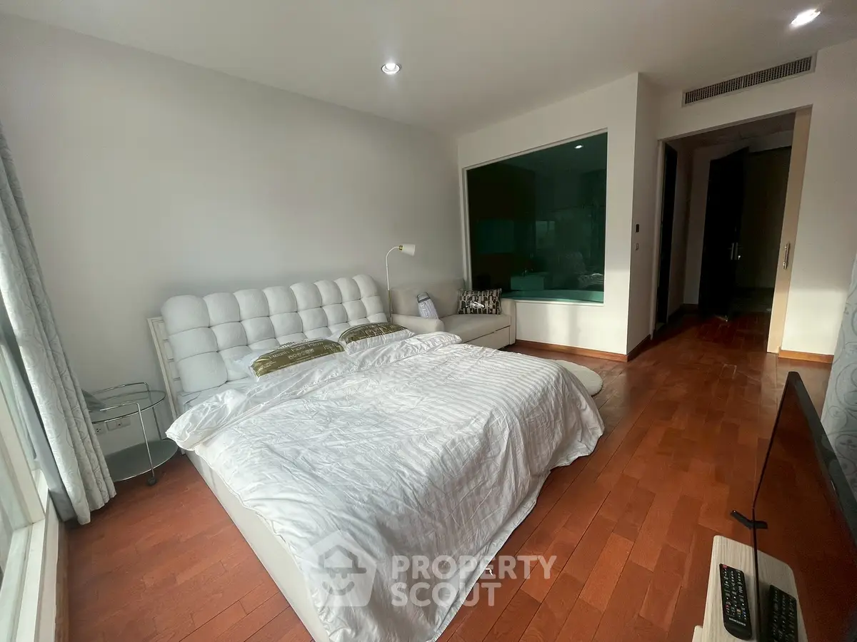 Spacious bedroom with elegant wooden flooring and modern decor