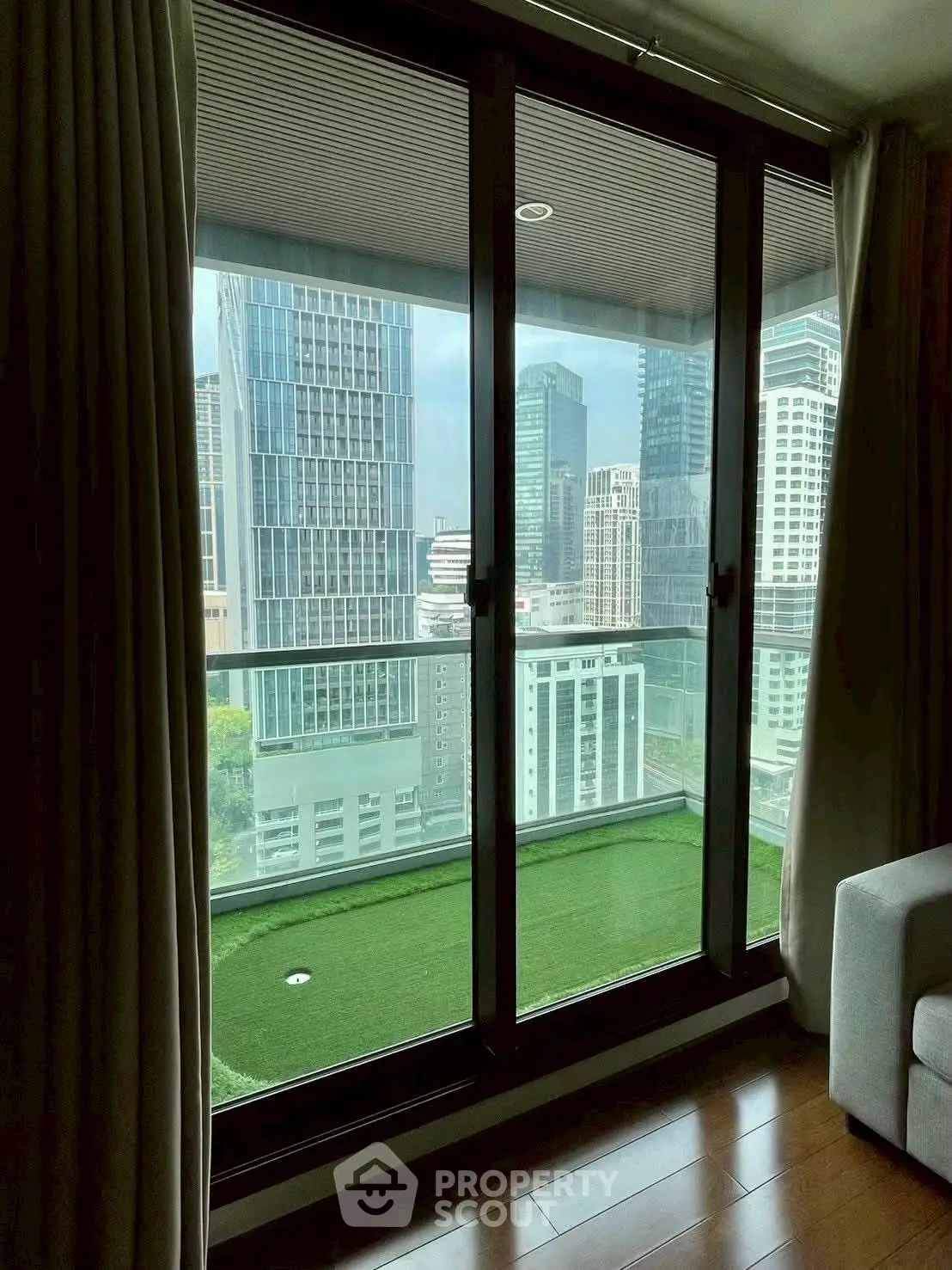 Modern high-rise apartment with stunning city view from large balcony windows.