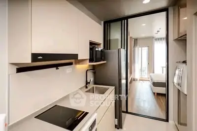 Modern kitchen with sleek appliances and open layout leading to a cozy living area.