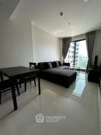 Modern living room with sleek furniture and large window offering city view.