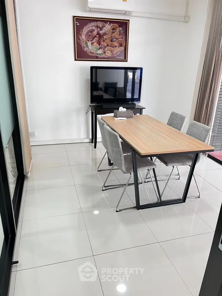 Modern study room with sleek table and chairs, featuring a wall-mounted TV and stylish decor.