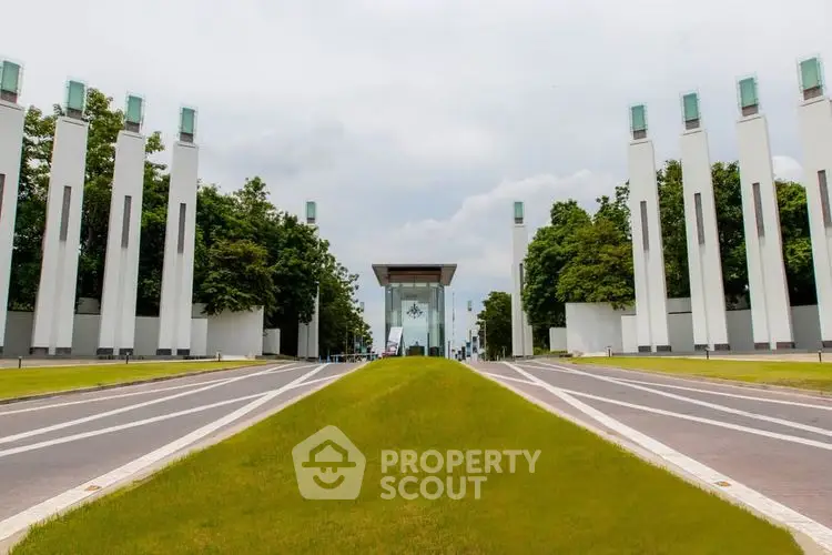 Modern architectural entrance with tall pillars and lush greenery