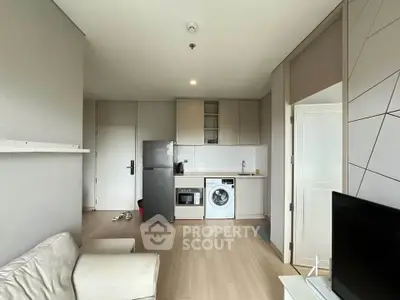 Modern apartment interior with kitchen and living area featuring washing machine and fridge.