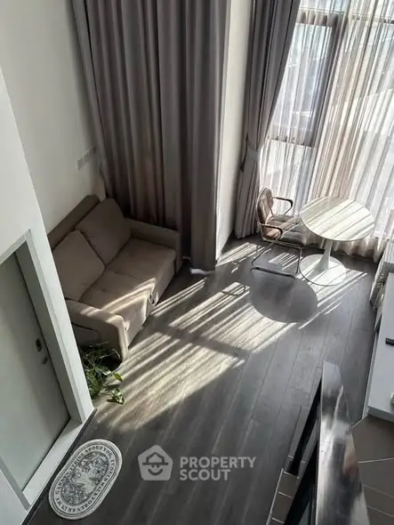 Modern living room with high ceilings and large windows, featuring cozy seating and elegant decor.