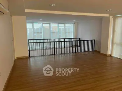 Spacious empty room with wooden flooring and large windows, ideal for customization.