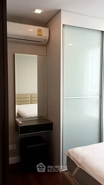 Modern bedroom with sleek design, featuring a sliding door closet and air conditioning unit.