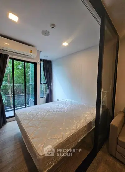Modern bedroom with large windows and balcony view, featuring a comfortable bed and stylish decor.
