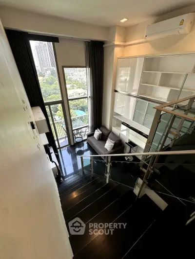 Modern loft apartment with high ceilings and large windows offering a stunning city view.