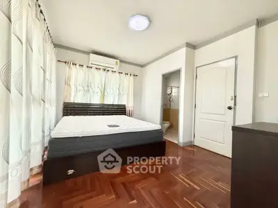 Spacious bedroom with hardwood floors and ensuite bathroom in modern apartment.