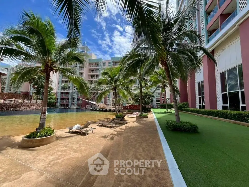 Luxurious condominium poolside with palm trees and sun loungers, perfect for relaxation and leisure.