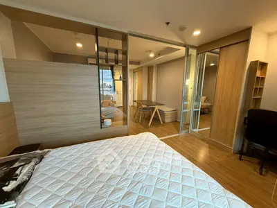 Modern bedroom with wooden flooring and sliding glass doors leading to a cozy living area.
