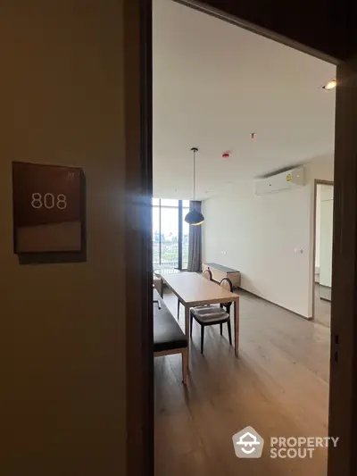 Modern dining area with wooden flooring and large window view in apartment 808.