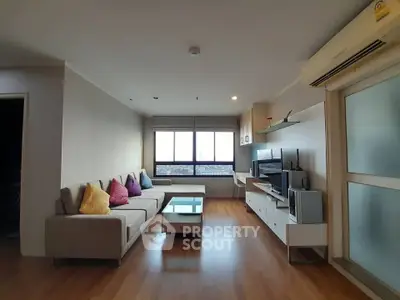 Spacious modern living room with large windows and stylish decor in a high-rise apartment.