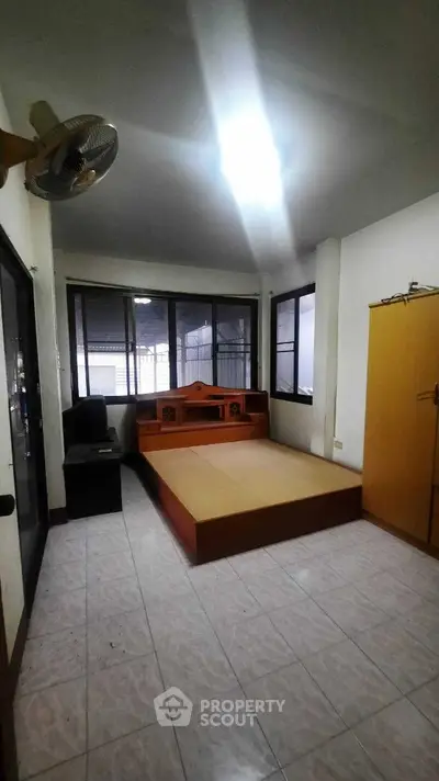 Spacious bedroom with large windows and wooden furniture, perfect for comfort and relaxation.