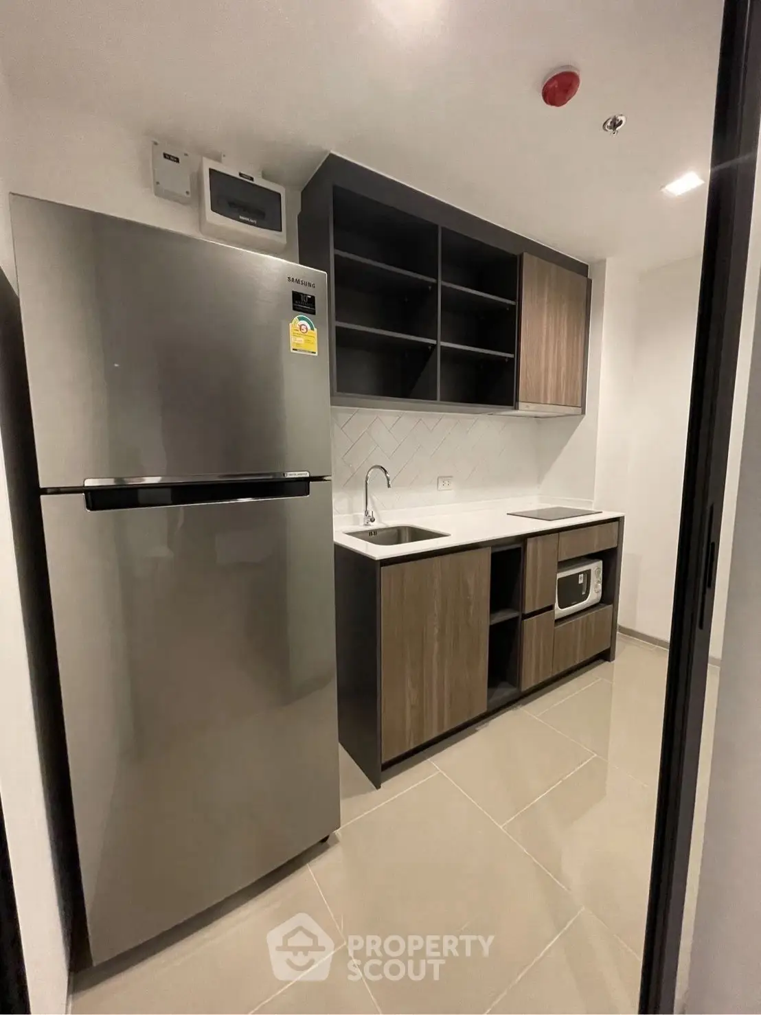 Modern kitchen with sleek appliances and minimalist design, featuring a stainless steel fridge and built-in oven.