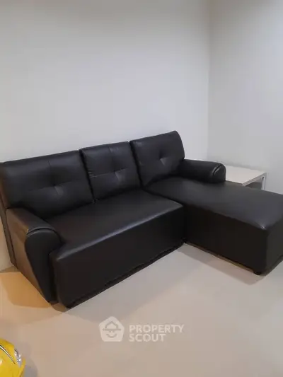 Modern black leather sofa in a stylish living room corner, perfect for contemporary interiors.