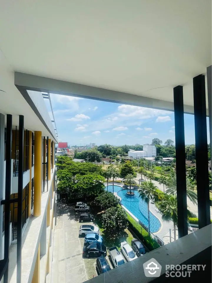 Stunning view from balcony overlooking pool and lush greenery in modern apartment complex.