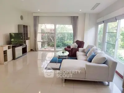 Spacious living room with modern furniture and large windows offering garden views.
