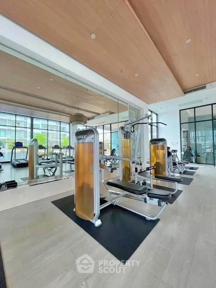 Modern gym with state-of-the-art equipment and large windows in a luxury residential building.