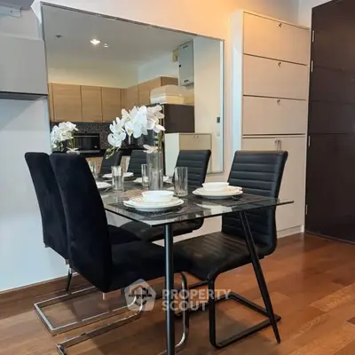 Modern dining area with sleek black chairs and glass table in stylish apartment.