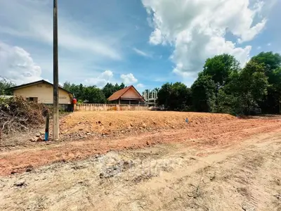 Spacious land plot with potential for development, surrounded by lush greenery and clear skies.