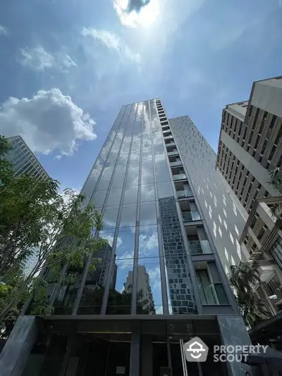 Stunning modern high-rise building with reflective glass facade and lush greenery in urban setting.