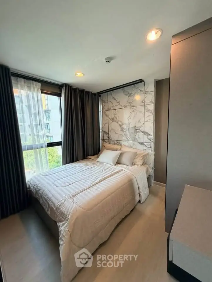 Modern bedroom with elegant marble accent wall and large windows in a stylish apartment.