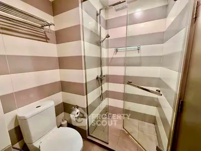 Modern bathroom with striped tile design and glass shower enclosure