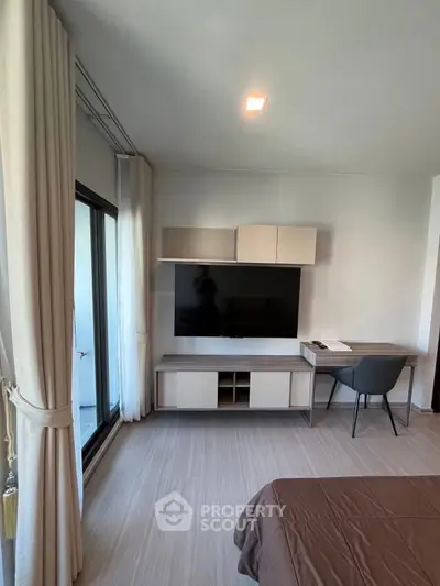 Modern bedroom with wall-mounted TV and sleek furniture, featuring a large window with curtains.