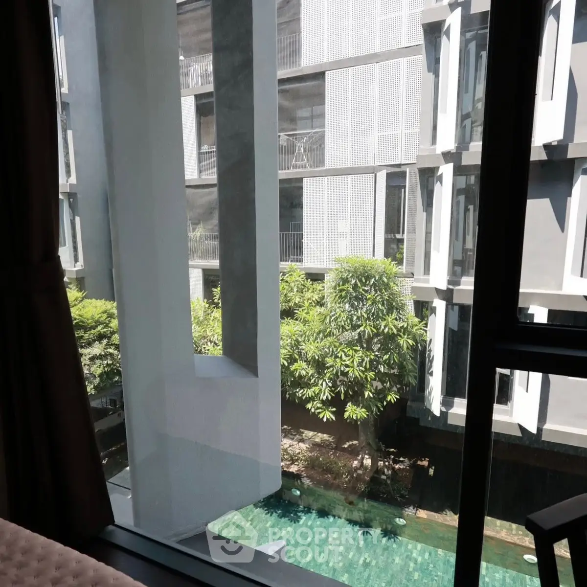 Modern apartment view with pool and lush greenery, offering serene urban living.