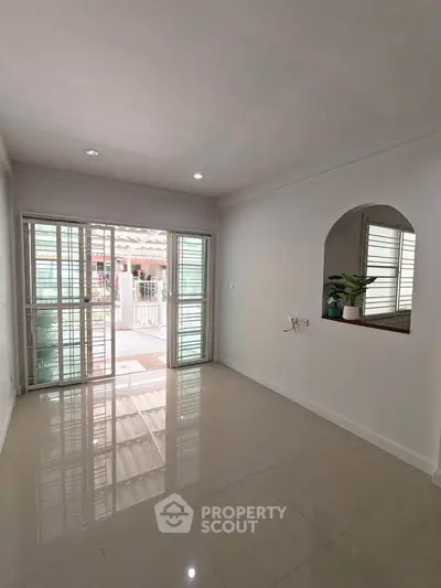 Spacious living room with large windows and glossy tiled floor, perfect for natural light lovers.