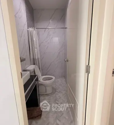 Modern bathroom with sleek design and elegant tiling, featuring a compact layout and contemporary fixtures.